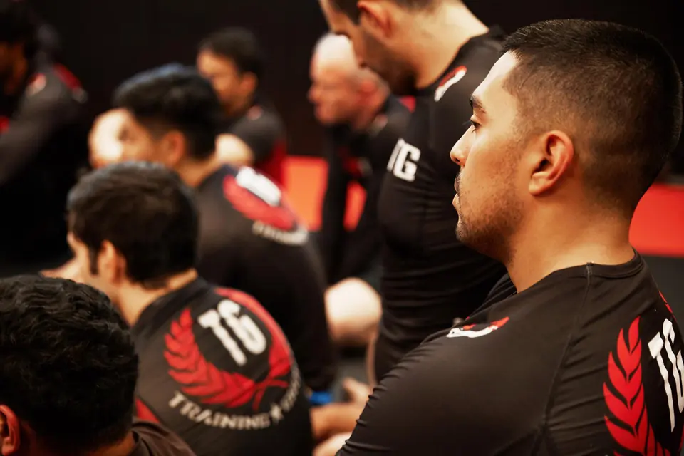 a student of jiu jitsu watching his instructor teaching class